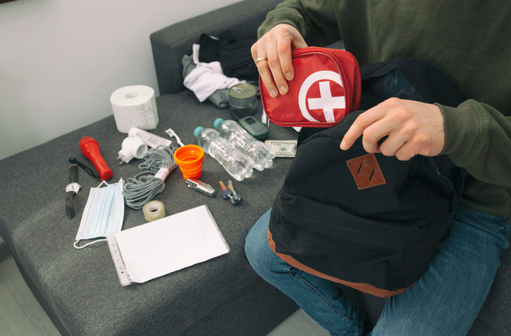 Parent organizing a first-aid kit with bandages, antiseptic wipes, and Dr. Nice's Boo-Boo Gel for kids